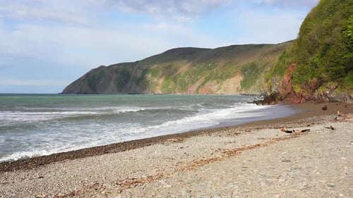 Waves crash into the pebble shores of Blacklands Beach in Lynmouth showing the tidal reach with a li