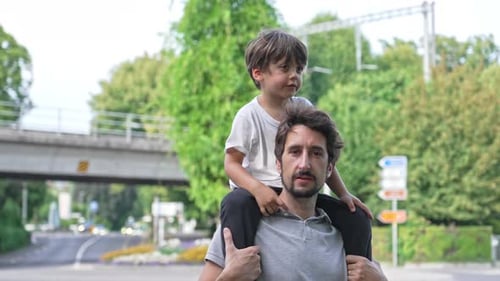 Man Carrying Child on Shoulders in Urban Park