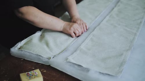 Person, die eine Holzlasur verwendet, um Stoff auf einem Hartholztisch mit einem Kreismuster zu schneiden