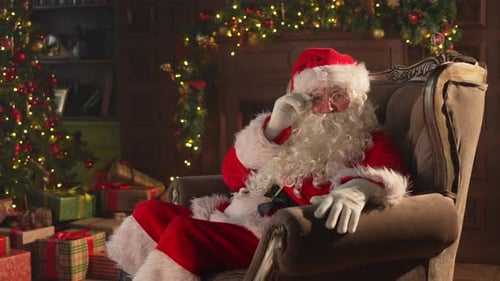 Santa Claus in armchair adjusts glasses in festive setting