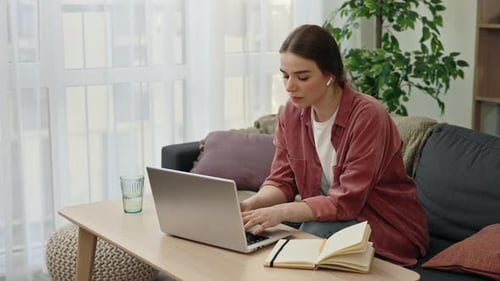 Woman Typing on Laptop at Home on Sofa