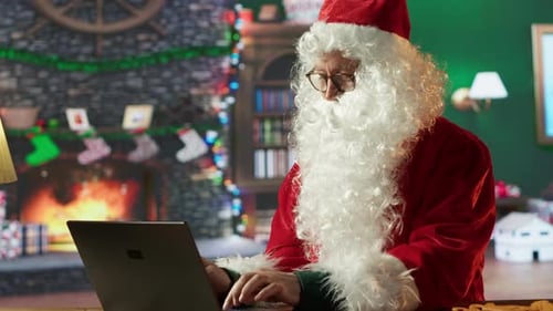 Santa Claus Typing on Computer in Festive Home