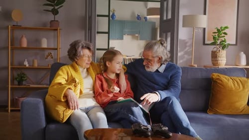 Grandparents Reading a Book with Granddaughter at Home