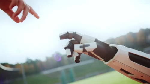 Horizontal View of Robot Arm and Human Hand Pointing Fingertips on Stadium Blurred Background of