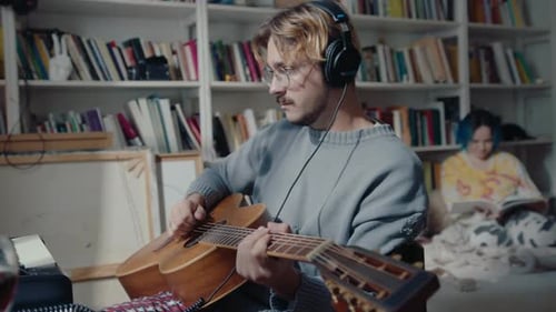 Man in Headphones Playing the Guitar at Home Music Studio