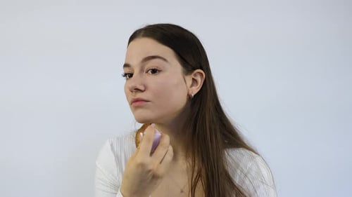 Young Woman Applying Makeup with Cosmetic Sponge