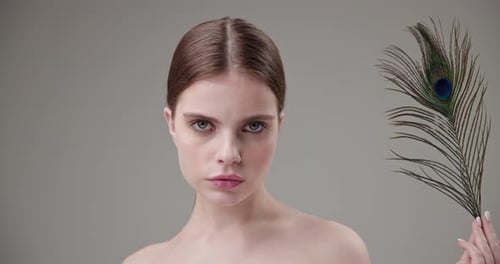 Attractive Model Posing with Peacock Feather