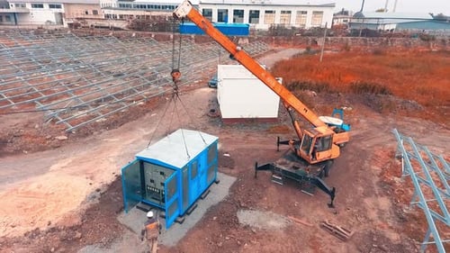 Emplacement préparé pour l'installation de panneaux solaires. Les travailleurs font le tour de la cabine d'équipement qui vient d'être installée avec une grue
