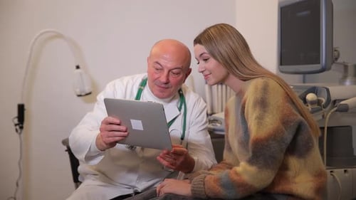 Doctor and Patient Reviewing Tablet in Medical Office
