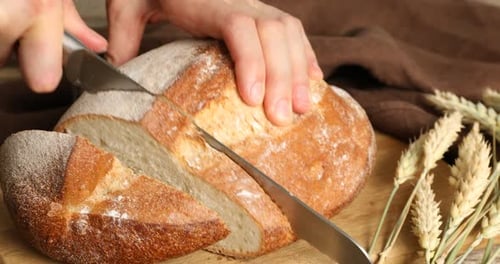 Woman cutting fresh bread at table, closeup