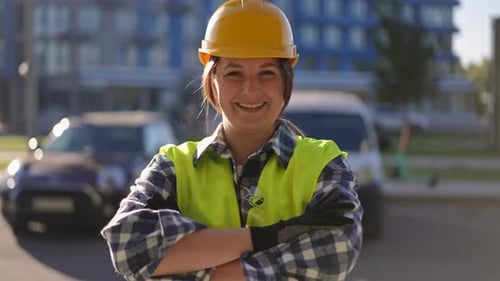 A Cheerful Female Construction Worker is Smiling on a Job Site While Wearing Safety Gear