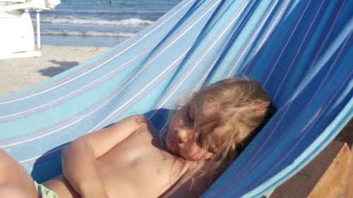 Kid Is Swinging In Hammock On The Sandy Beach