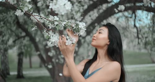 Woman Smelling Apple Blossoms in a Public Park