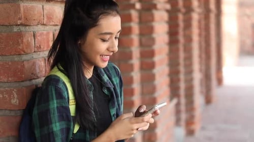 Video clip of a female college student typing text on her mobile phone on the college campus.