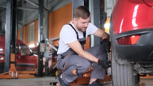 Smiling Mechanic Changing Car Tire in Repair Shop