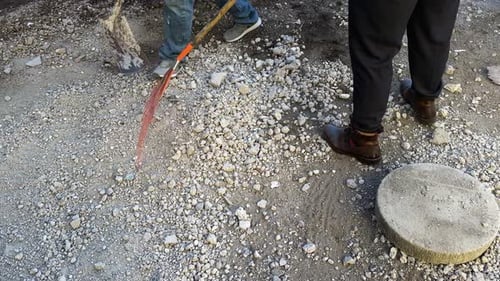 Workers clearing gravel with shovels at construction site during manual labor
