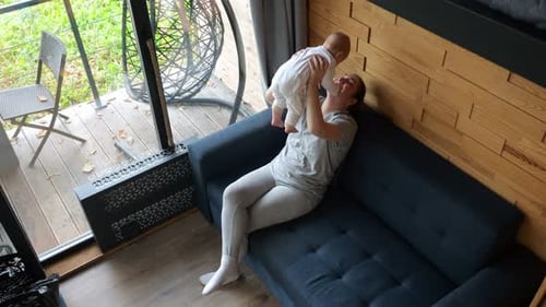 Loving Mother Lifting Infant in Airy Home
