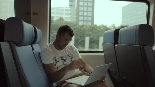 Mann im Zug unterhält sich mit Laptop