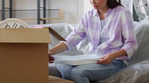 Woman unpacking picture frame at new home
