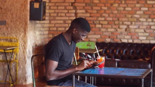 technology, youth - black man at pub scrolls the keyboard of the tablet