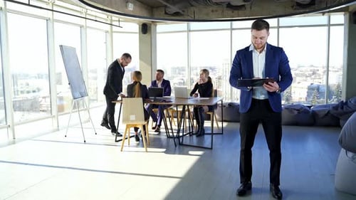 Handsome businessman looking into tablet in background of meeting. Business meeting.