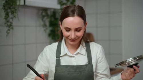 Woman Tasting Food with Ladle in Kitchen