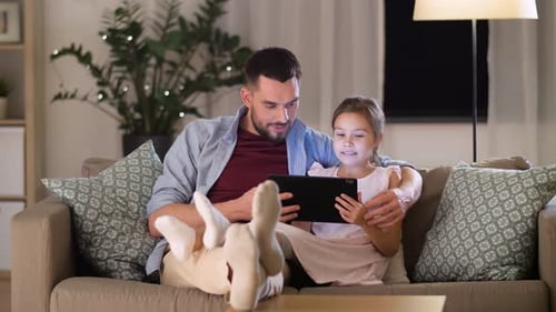 Father and Daughter Using Tablet on Couch at Home