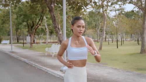Young fitness woman in sportswear jogging in city park