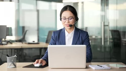 Young Woman Works At Computer Wearing Headset