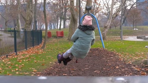 Girl Swinging on a Zip Line in a Playground During Autumn