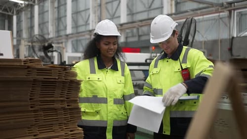Factory Workers Discussing Documents in Cardboard Warehouse