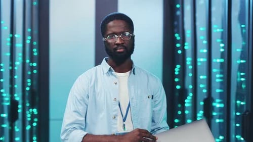 Man Smiling in Data Center Holding Laptop