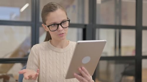 Woman Joyfully Communicating on Tablet in Modern Office