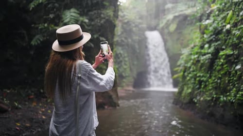 Carefree Blonde Woman in Straw Hat Take Photos Breathtaking Mountain Waterfall in Wild Nature Girl