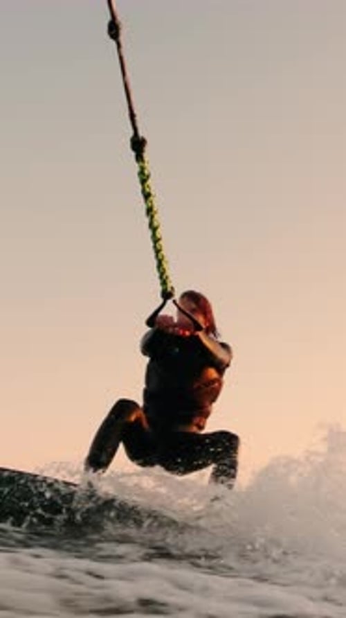 Woman Wakeboarding at Sunset Holding Rope