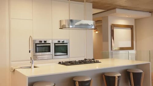 Modern kitchen with island, bar stools, and stainless steel appliances in home