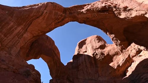 Vue inclinée vers le bas sur la Double Arche du parc national des Arches par une journée sans nuages avec des touristes qui explorent