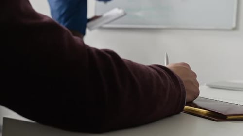 Männlicher Manager schreibt an Bord und bespricht den Wochenarbeitsplan mit einem Kollegen im Büro