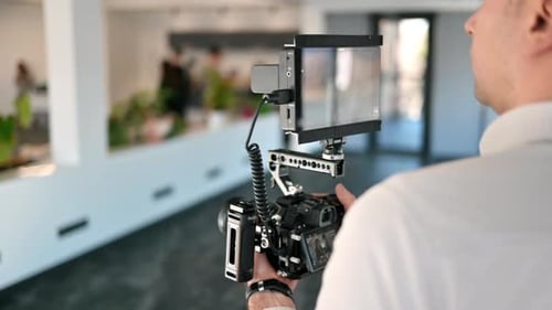Professional photographer holding a camera with external display. Shooting in an office. Slow motion