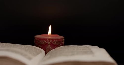 Close up of an open book surrounded by candlelight