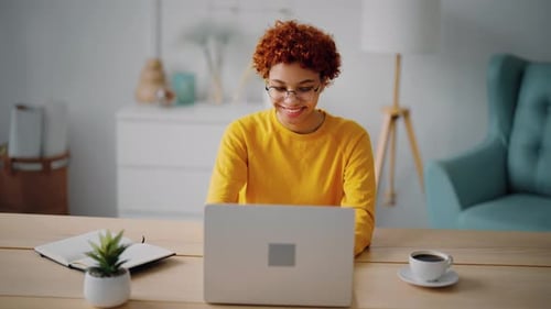 Positive African American Woman Office Worker Doing Job on Laptop Sitting on Workplace in Modern