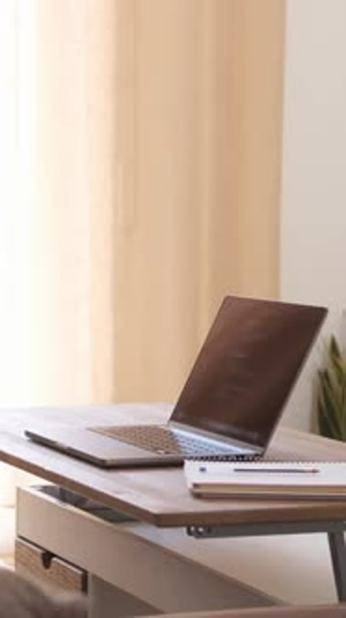 Laptop and Notepad on Table Next to Window