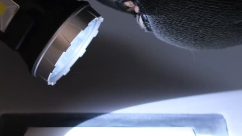 Masked Person Looking with Flashlight in Dark Room