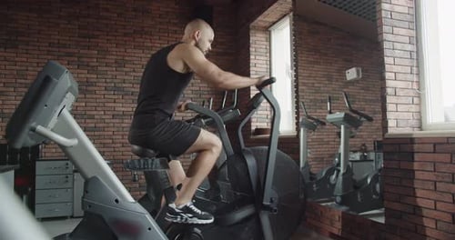 A Man Does Sports on an Exercise Bike in a Gym