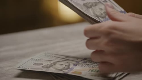 Woman Counts Stack of United States One Hundred Dollars