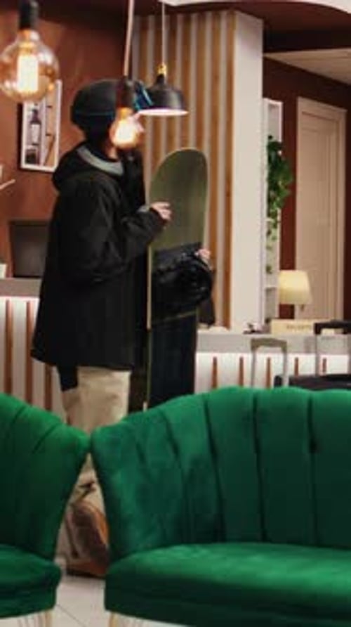Skier Arriving at Hotel with Snowboard and Helmet