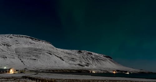 time lapse of northern lights in iceland with mountain covered with snow