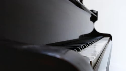 Close up of old, wooden baby grand piano keys against white background. Eye level, pivoting, 24fps,