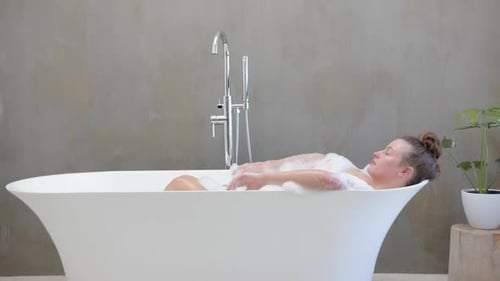 Relaxing in bathtub, woman enjoying spa day with bubbles and peaceful ambiance