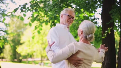 Happy senior couple dancing together in a summer city park romance